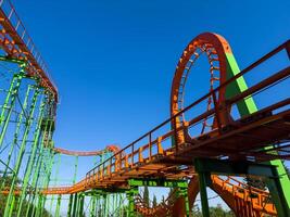 Orange roller coaster at an amusement park with cloudy blue sky, hang out and have fun outdoor at theme park on summer holiday. photo