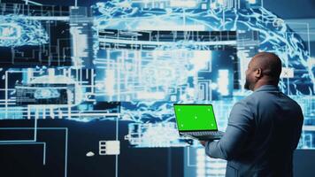 Black high tech engineer holding phone with isolated mockup screen, reviewing predictive analytics and neural networks systems for virtual intelligence and platform innovation. Camera A. video
