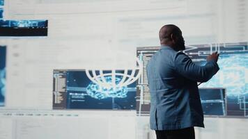 Black software expert focusing on programming language for innovation, reading binary code on terminal window. Reviews code development for data science. Modern futuristic coding life. Camera A. video