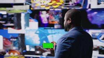 African american user holding a phone with isolated mockup display, digital system of networks and apps on dashboard. Highlighting the integration of AI and fintech. Multitasking. Camera A. video