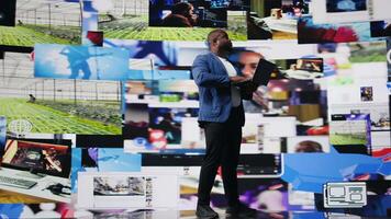 African american specialist engaging with media dashboards screens, emphasizes networking with AI and technology. Tech driven guy showcases online platforms and internet communication. Camera A. video