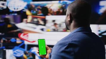 Professional media expert in a high tech space holds green screen, leveraging social media, internet big data and cloud systems. Person engaging followers to boost digital presence. Camera A. video