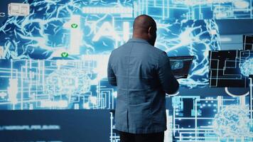 Tech savvy black engineer working with AI brain data visualization, illustrating computer science and automation tools for deep learning. Implementing neural networks systems. Camera A. video