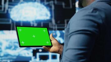 African american engineer shows tablet with isolated mockup display, examining predictive analytics and neural networks for data processing automation and innovation. Cybernetics. Camera B. video