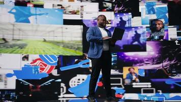 Black social media manager browsing high tech environment with app interfaces, infographics and social networking feeds. Big data on social media platforms, multimedia. Camera A. video