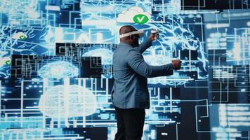 Black businessman using advanced technology VR headset tools to explore data science, automation and AI ethics in a digital data processing environment. Works on machine learning. Camera A. video