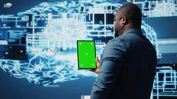 African american expert holds tablet with isolated screen next to cloud computing systems, focused on AI brain development and machine learning for innovation. Smart tech data science. Camera A. video