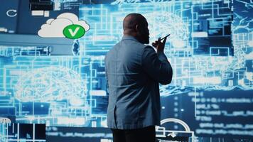 African american IT specialist calling a technician on his smartphone, talking about automation via neural networks systems. Businessman discuss about coding and data processing. Camera A. video