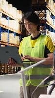 Vertical Asian industrial employee organizes goods and processes online shopping orders, coordinating delivery. Man handles packaging and manages inventory, working efficiently for clients. Camera A. video