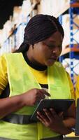 Vertical Large scale warehouse team manages e-commerce order processing, checking packages placed on big industrial racks in the depot. Staff in hi vis vests look at boxes pallets. Camera B. video