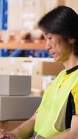 Vertical Depot asian worker processing online shopping orders on computer, managing shipment details and awb numbers on professional software. Handles packaging and manages inventory. Camera B. video
