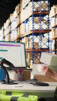 Vertical Male worker managing package labeling using shipment details adhesive tags, handling order processing and preparing the packages for distribution. Online shopping fulfillment center. Camera A. video