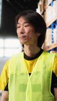 Vertical Warehouse employee in hi vis vest preparing packages for local delivery, processing custom orders and handling merchandise within large business operation focused on e-commerce. Camera B. video