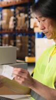 Vertical Male worker managing package labeling using shipment details adhesive tags, handling order processing and preparing the packages for distribution. Online shopping fulfillment center. Camera B. video