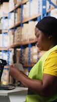 Vertical Woman staff managing package labeling using shipment details adhesive tags, handling order processing and preparing the packages for distribution. Online shopping fulfillment center. Camera B. video