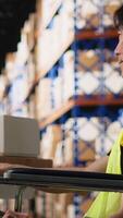 Vertical Employee with physical impairment managing warehouse logistics, working on processing orders from e-commerce large business. Supply and demand operations and inventory control. Camera B. video