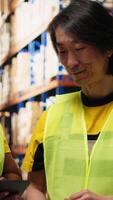 Vertical Diverse employees overseeing order details shipments for distribution, checking digital stock inventory and cargo pallets on industrial racks. Large scale express delivery. Camera B. video