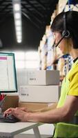 Vertical Call center employee assisting customers in a fulfillment center, handling inventory control and package tracking. Asian man resolving issues related to delivery delays or wrong addresses. Camera A. video