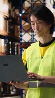 Vertical Multiethnic staff processing e-commerce orders and reviewing invoices, organizing cargo goods inside industrial warehouse space with storage racks. Smooth delivery and quality control. Camera B. video