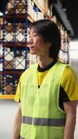 Vertical Asian male employee oversees product handling and order fulfillment, ensures inventory control using technology and packages coordination for efficient local delivery service. Camera A. video