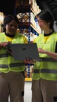 Vertical Multiethnic staff processing e-commerce orders and reviewing invoices, organizing cargo goods inside industrial warehouse space with storage racks. Smooth delivery and quality control. Camera A. video
