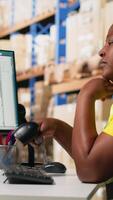 Vertical African american overworked woman struggling to stay awake, dealing with burnout after a long shift of processing orders in industrial warehouse space. Exhausted staff member. Camera B. video