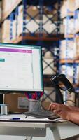 Vertical Female warehouse clerk registering barcodes for packages, scanning the shipping labels and awb tags on cardboard boxes. Fulfillment center distribution operations for e-commerce. Camera B. video