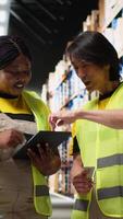 Vertical Diverse staff members using tablet for order processing and fulfillment, working on packing goods in warehouse space and ensuring easy import export products distribution. Camera B. video