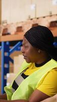 Vertical African american and asian workers reviewing shipment route and details for the real time parcel tracking info on computer software, managing order fulfillment in a logistics center. Camera B. video