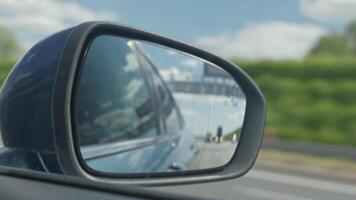 Car side mirror showing the blind spot warning light activated as another vehicle overtakes on the highway video