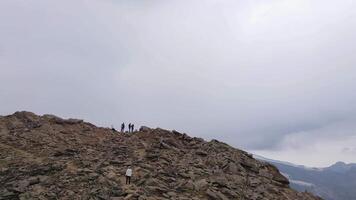 Aerial view of hikers reaching a mountain summit in the Caucasus region video