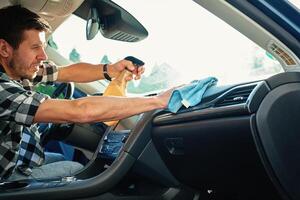 Person Cleaning Car Dashboard with Spray and Cloth photo