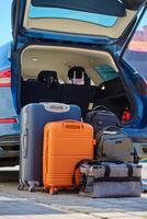 Luggage standing near car with open trunk ready for travel or moving photo
