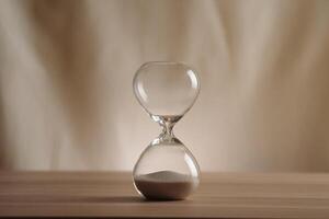 A simple hourglass on a wooden table with a beige backdrop, symbolizing time flow and minimalistic living. Represents timeless themes in a creative, uncluttered presentation for stylish concepts. photo