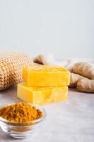 Homemade natural turmeric soap and ingredients on the table vertical view photo