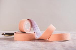 Neutral colored kinesio tapes for face lifting and scissors on the table photo