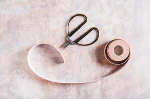 Close up of neutral colored kinesio tape for face lifting and scissors on the table top view photo