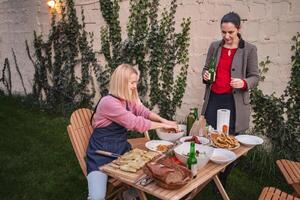 Friends enjoying a cozy outdoor feast in a garden setting at dusk photo