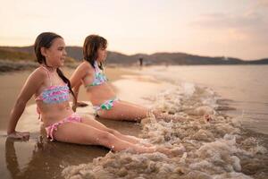 Sisters enjoying a sunny day at the beach playing with gentle waves photo