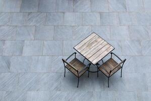 set of wooden table and two chairs on stone floor outdoor photo