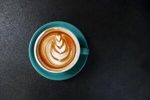 one cup of hot latte with saucer on dark rustic cement background photo