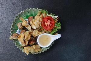 fried crispy meat spring roll with plum sauce and mixed vegetable served on circle zig zag plate photo