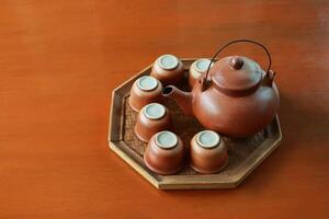 Set of baked clay kettle and cups on octagon tray. photo