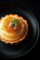 Delicious pear tart with poppy seeds and edible gold on black plate photo