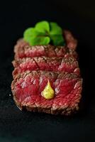 Slices of roast beef with mustard and basil on black background photo