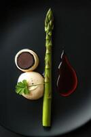 Green asparagus with truffle cream and balsamic glaze on black plate photo