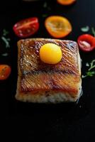 Grilled fish fillet with cherry tomatoes and parsley on black background photo