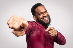 Hey, You. Smiling African American Man Pointing Fingers At Camera Posing Standing Over White Background In Studio. Cheerful Black Guy Gesturing I Choose You Concept. photo