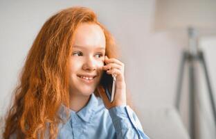 Phone Talk And Communication Concept. Closeup portrait of cheerful casual red-haired female kid making call using smartphone, teenager talking to parents or friends, enjoying conversation photo