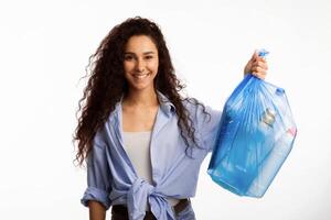 Smiling Woman Posing With Plastic Garbage Bag Showing Sorted Waste Standing Over White Studio Background. Keep Environment Clean And Sort Your Junk, Litter Disposal Concept photo